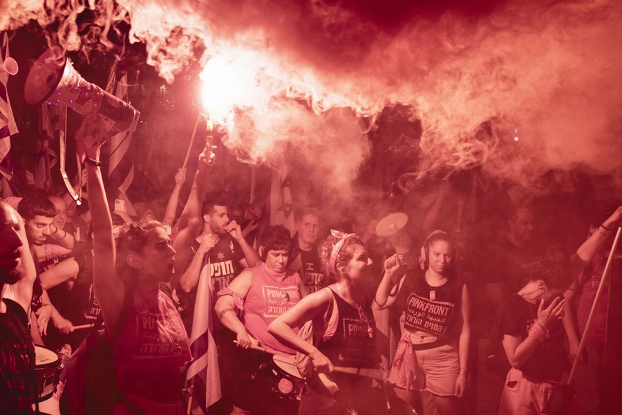 Protesters chant beneath a cloud of smoke from flares.