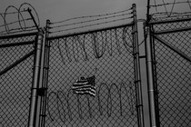 An American flag behind barbed wire fence