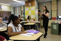 A woman stands at the front of a classroom as her students listen.