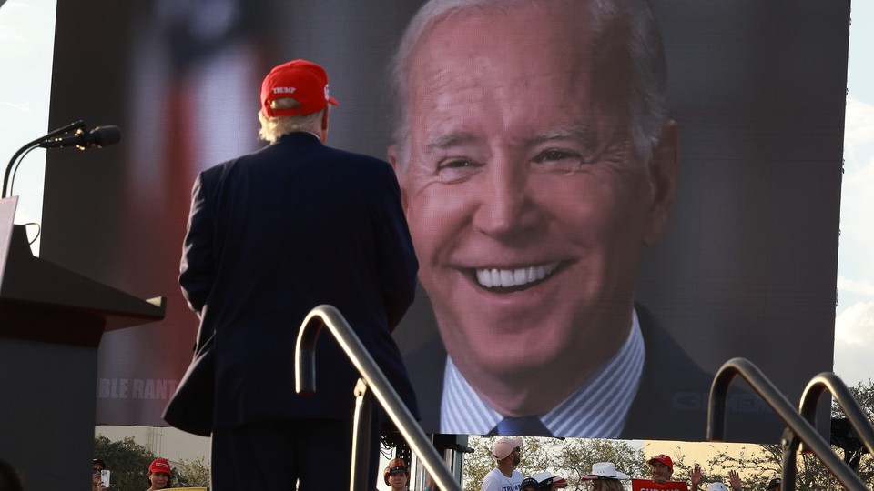 Trump stands in front of a photo of Biden