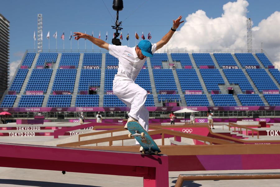 A skateboarder rides on a rail in an empty skatepark.
