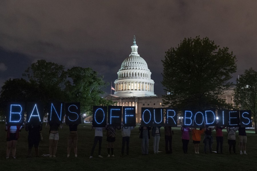 A line of protesters stands in front of the U.S. Capitol building holding up signs that read 'bans off our bodies.'