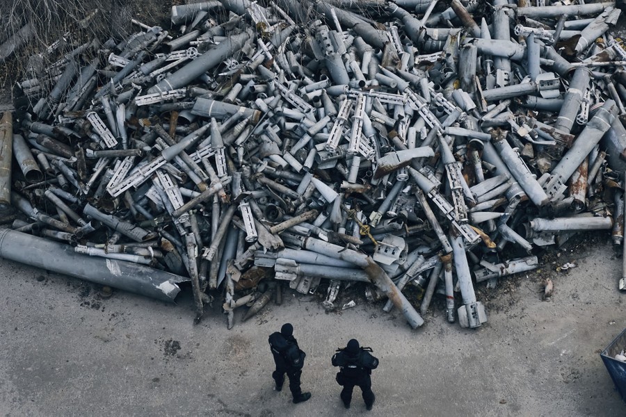 An elevated view of two police officers looking at a huge pile of collected fragments of rockets