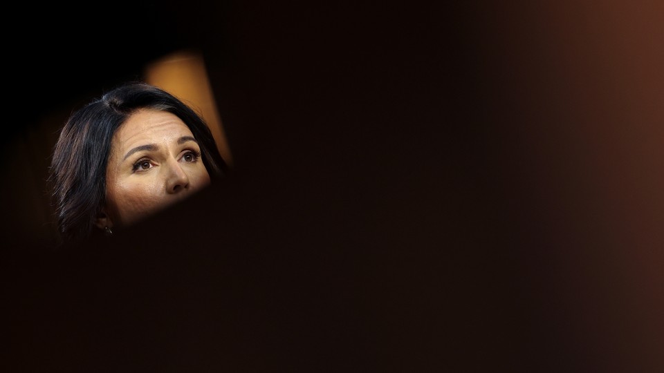 Tulsi Gabbard's face, mostly exposed by a dark blur