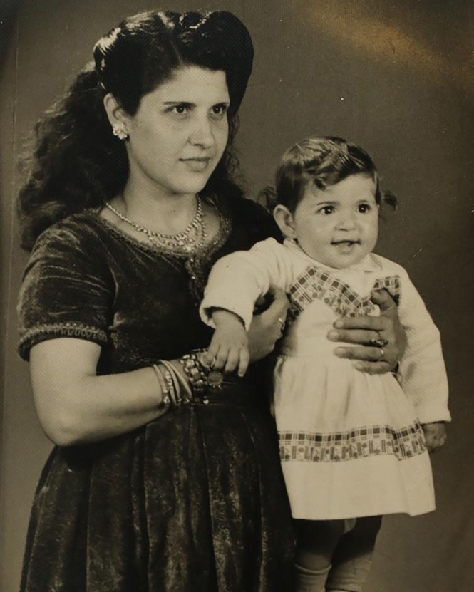 A woman holding a baby in traditional Palestinian clothing.