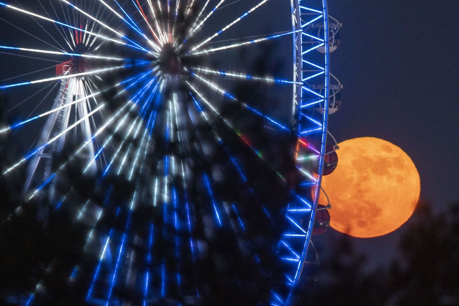 The moon beyond a Ferris wheel.