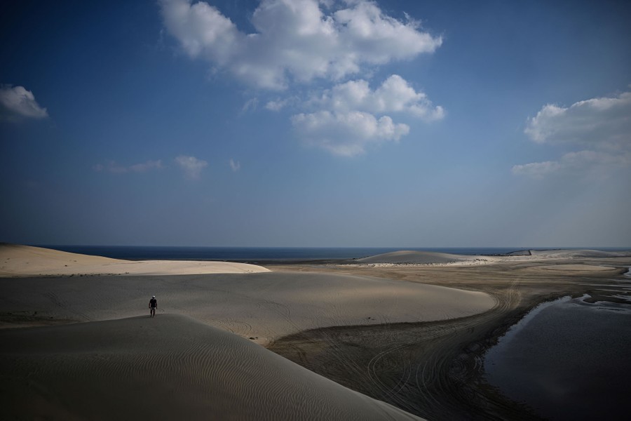 A man walks on sand dunes.