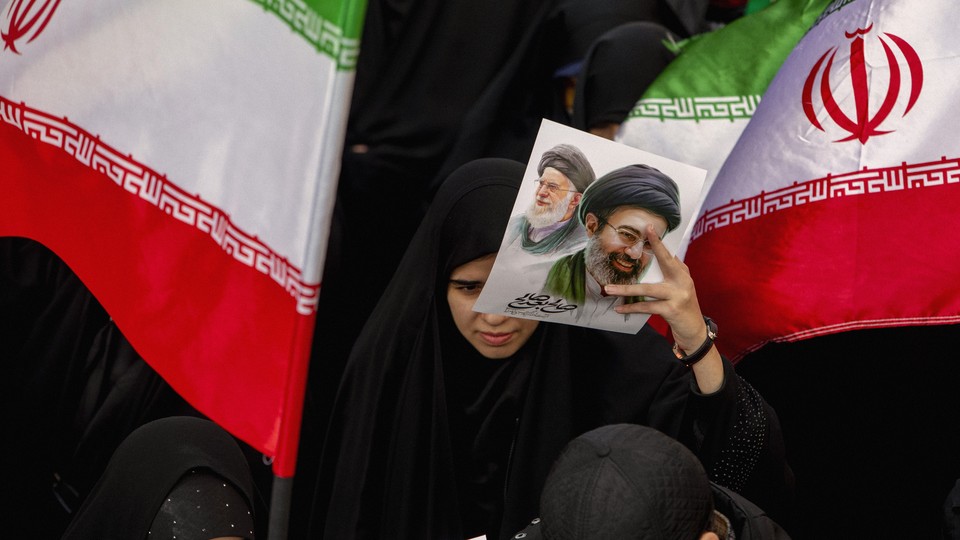 A photo of an Iranian holding a flyer picturing two supreme leaders