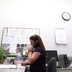 A woman uses an office phone at a desk.