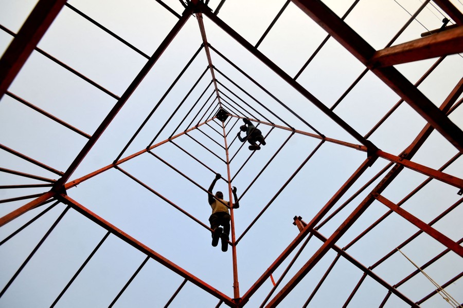 Workers assemble the frame of a tent, photographed from below.