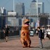 A person in a T-rex costume on a riverside walking path in London