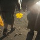 Two people walking in a park, carrying a yellow bag and a yellow leaf, photographed from behind