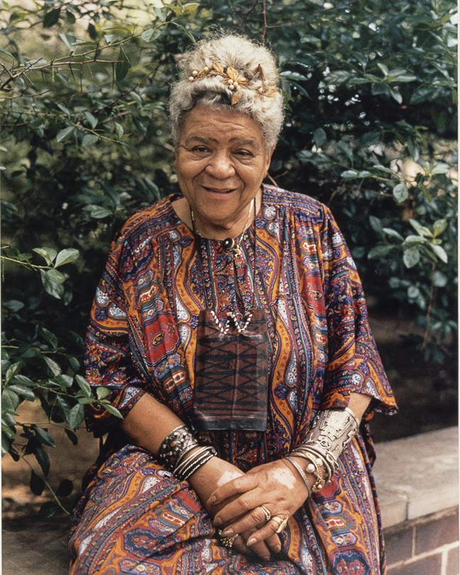 A color photograph of Audley Moore seated on a brick ledge