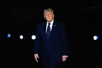 A photograph of Trump in a blue suit against a dark background