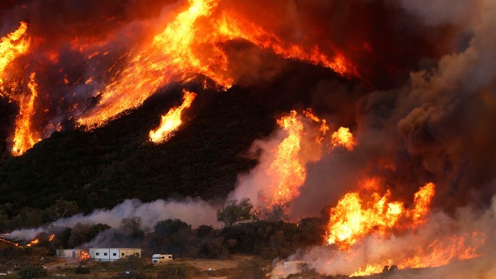 Flames whipped by strong winds burn though a hillside before destroying camper vans during the Blue Cut fire.