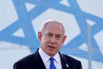 A photograph of Benjamin Netanyahu speaking in front of a large Israeli flag