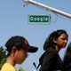 People walk past a street sign that reads "Google."