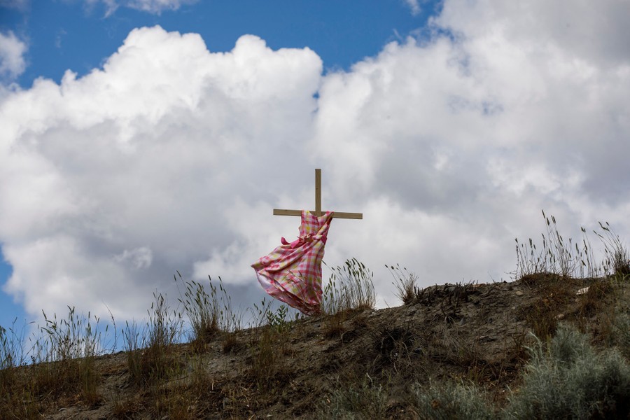 A child's dress placed on a stake on a hillside blows in the wind.