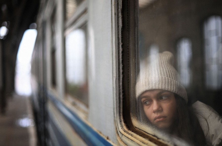 A girl looks out a window as she waits inside a train.