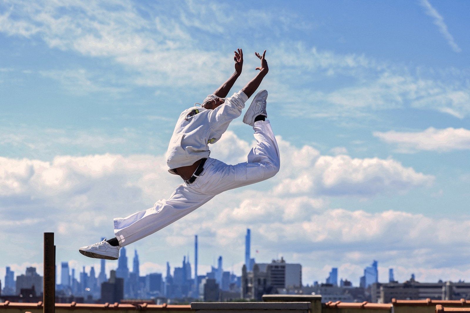 A dancer leaps and poses on a rooftop in New York City.