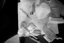 syringes and bandaids splayed out on a paper towel, against a black background