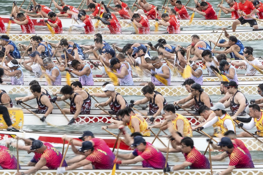 Rowers in at least eight long dragon boats paddle at the start of a race.
