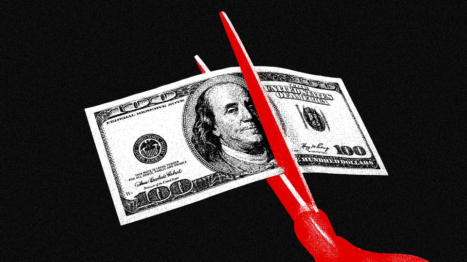 Red scissors cutting a $100 bill