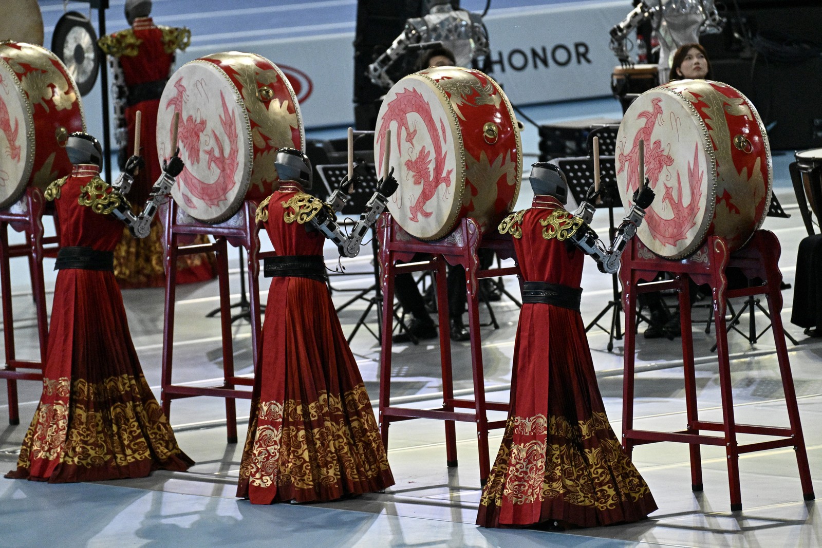 Robots wearing traditional costumes play drums during an opening ceremony performance.