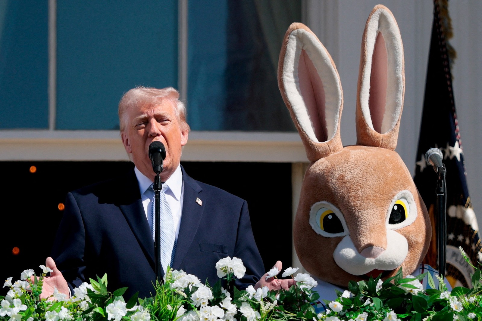 Donald Trump speaks beside the Easter Bunny on a balcony.