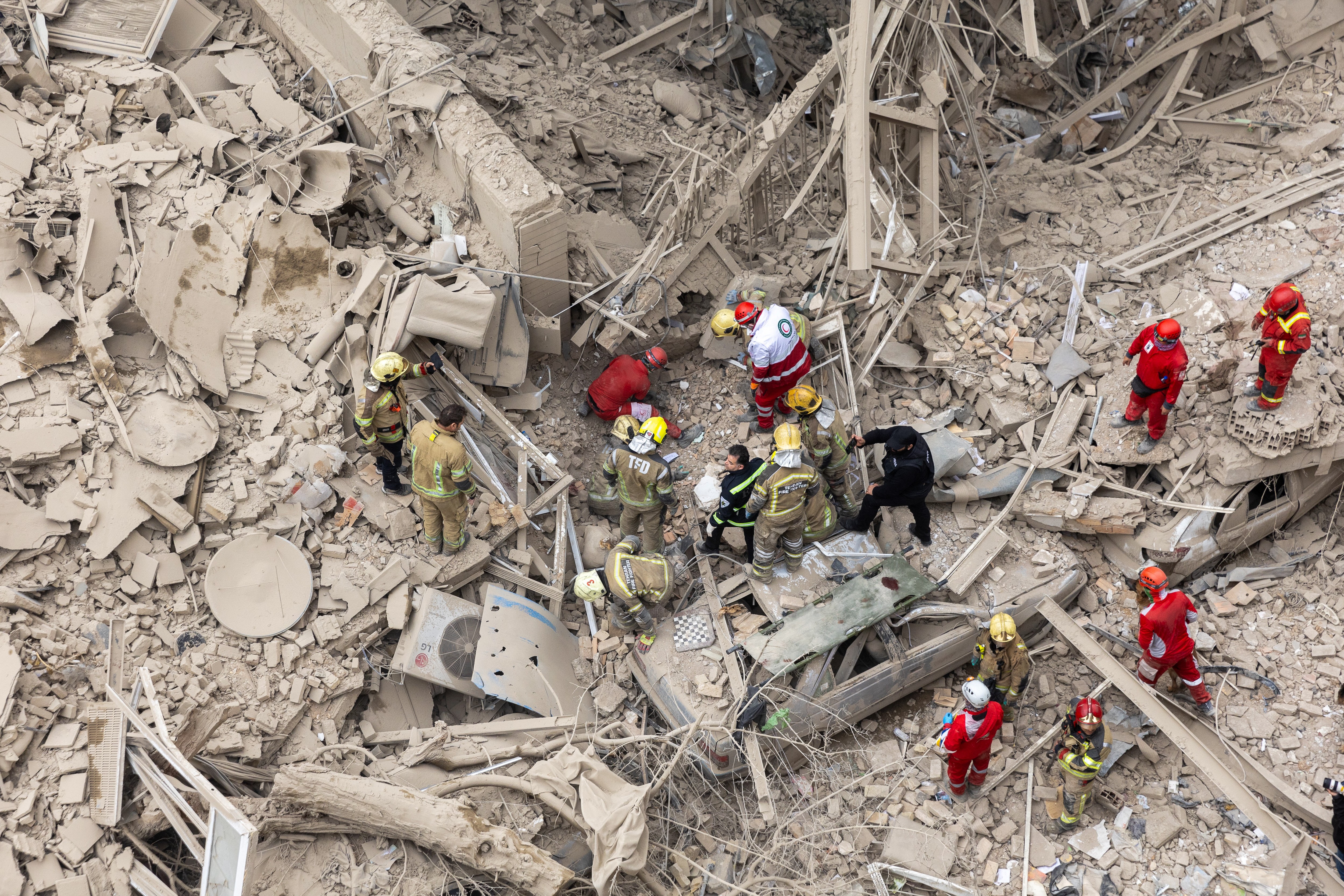Emergency crews search for people trapped in rubble of a large building.