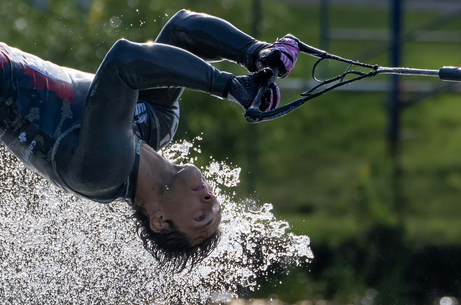 A water-skier, seen twisting in mid-air during a competition, with splashing water below.