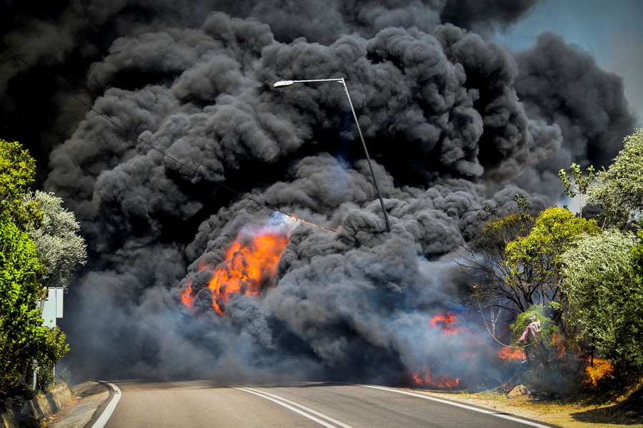 Black smoke along a roadway fills the frame.