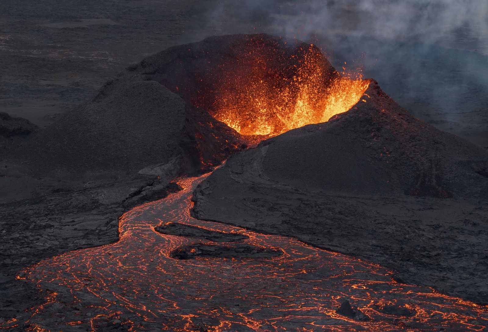 Lava erupts and flows from a volcanic crater.