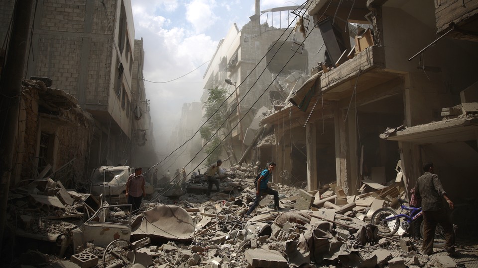 Syrians walk amid the rubble of destroyed buildings