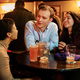 photo of 3 people talking and drinking pints at small round table in pub