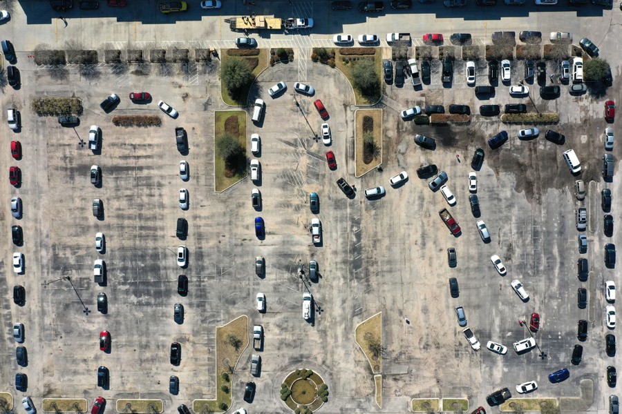 Dozens of cars wait in a line that snakes through a parking lot.