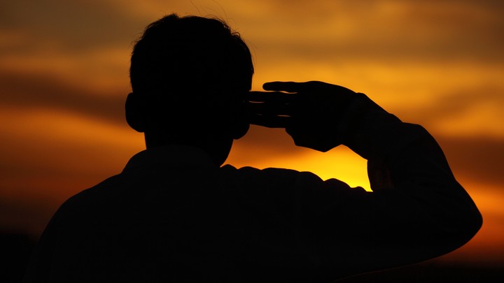 A boy salutes at sunset