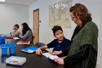 An adult and student look at a worksheet together.