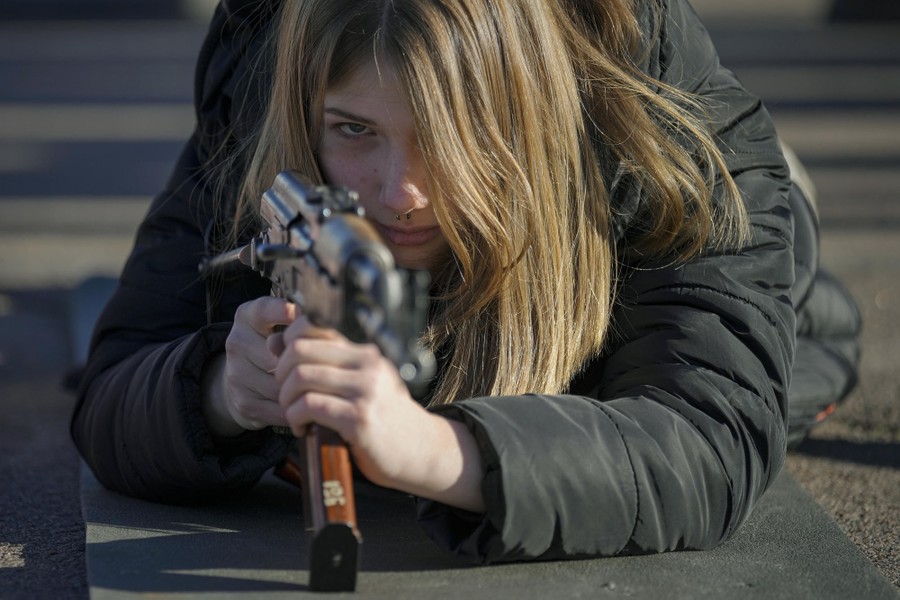 A young woman holds a weapon during a basic combat training.