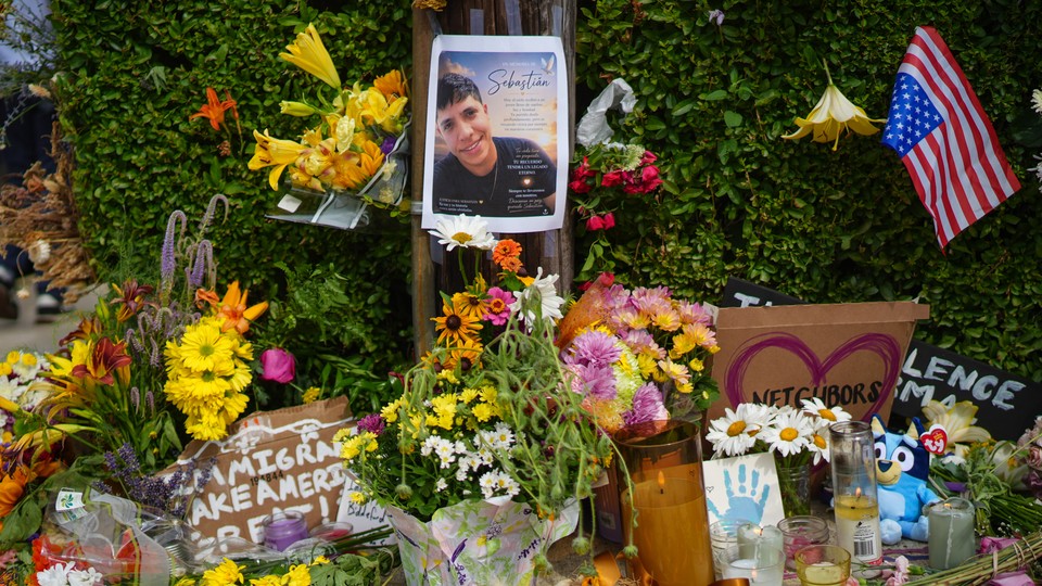 A memorial for a Colombian man killed in Maine during an ICE vehicle stop includes flowers, a photo of him, and cardboard signs including one that says, "Immigrants Make America Great!"