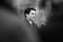 A black-and-white photo of Justin Trudeau looking down at a podium.