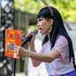 The drag queen Yuhua Hamasaki holds up "The Family Book" on an outdoor stage holding a microphone.