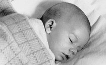 Black-and-white photograph of a baby sleeping under a blanket