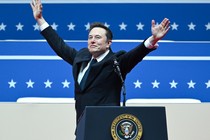 Elon Musk raises his arms in front of the presidential podium