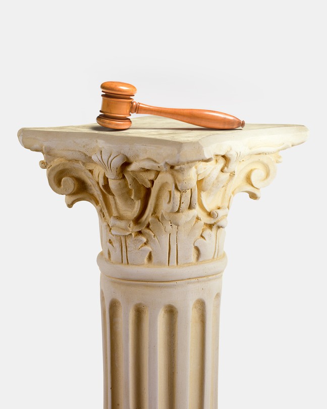 A gavel atop a Greek-looking column