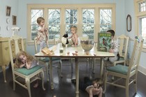 A photograph of children on and around a dining-room table, making a mess