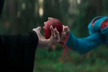 The Evil Queen disguised as an old lady hands an apple to Snow White