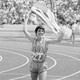 photo of the marathoner Joan Benoit Samuelson jogging while holding up an American flag