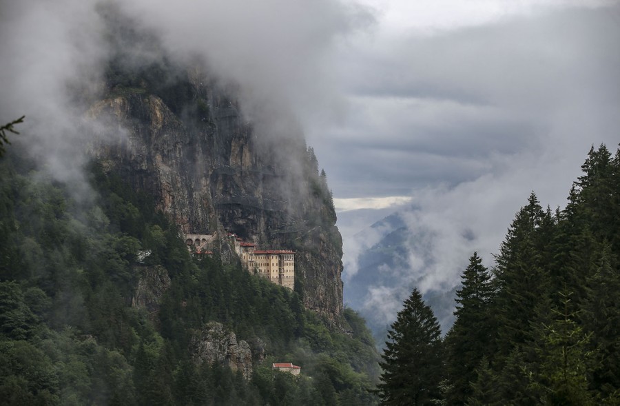 A view of a cliffside monastery on a cloudy day.