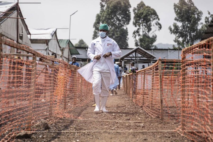 A health-care worker walks past temporary fencing set up to isolate patients in an mpox treatment center.